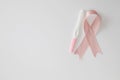 Pink satin breast cancer awareness ribbon with blank pregnancy test isolated on white background top view