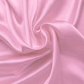 Pink satin fabric texture, silk background with folds. Wavy abstract pattern, luxury shiny bed sheet, soft textile. Flow effect. Royalty Free Stock Photo