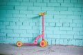 Pink scooter standing near blue brick wall Royalty Free Stock Photo