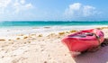 Pink sea kayak parked on a beach on a hot sunny day next to a turquoise blue sea in an exotic travel destination