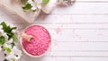 Pink sea salt in bowl, towels and flowers on white wooden backg Royalty Free Stock Photo