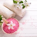 Pink sea salt in bowl, towels and flowers on white wooden backg Royalty Free Stock Photo