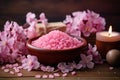 Pink sea salt in a clay bowl with flowers and a candle on a wooden background, surrounded by petals Royalty Free Stock Photo