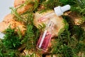 Pink serum in a transparent glass bottle on natural moss and stone background.