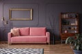 Pink settee against grey wall with mockup of gold frame in elegant living room interior. Real photo Royalty Free Stock Photo