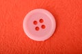 Pink sewing button isolated on a red background