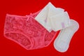 Pink women`s lace panties with sanitary napkin on red background Royalty Free Stock Photo