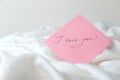 A pink sheet of paper with the words `I love you` on white crumpled fabric