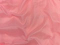 Pink silk fabric texture top view. Red coral glossy satin background. Fashion color feminine clothes trend Royalty Free Stock Photo