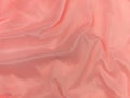 Pink silk fabric texture top view. Red coral glossy satin background. Fashion color feminine clothes trend Royalty Free Stock Photo