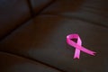 Pink silk ribbon on leather sofa, Breast cancer awareness mont concept for background.