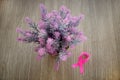 Pink silk ribbon on wooden desk with sweet pink and purple bouquet, Breast cancer awareness mont concept for background.