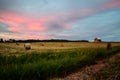 Bales of hay in field with pink sky and barn sunset scenic landscape Royalty Free Stock Photo