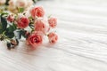 Pink small roses on wooden background in light, space for text.