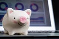 Pink smiling piggy bank on laptop displaying online financial chart and graph using as online stock trading, asset allocation or Royalty Free Stock Photo