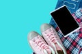 Pink sneaker, scott shirt, torn jean, smart-phone isolated on bl