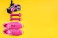 Pink sneakers, dumbbells and sport gloves lie in a row on a yellow background Royalty Free Stock Photo