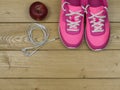 Pink sneakers and a red Apple on a wooden floor. The view from the top. Royalty Free Stock Photo