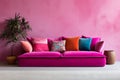 Pink sofa with colorful eclectic pillows near a textured wall. Modern interior for mockup, wall art. Promotion background with