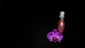 Pink spray plastic bottle with purple orchid on black background Royalty Free Stock Photo