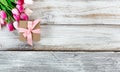 Pink springtime tulips and gift box on white rustic wooden board