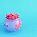 Pink St. Patricks pot of golden coins with clover leaves in the front on bright blue background in pastel colors. Minimalism