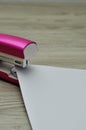 A pink stapler with papers