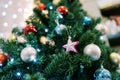 Pink star next to silver and blue balls hangs on a Christmas tree Royalty Free Stock Photo