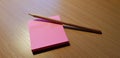 Pink sticky notes and a wooden graphite pencil on a wooden office table