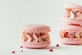 Pink strawberry macaroons decorated with golden petals and freeze-dried red berries stacked together in a pile. Traditional French