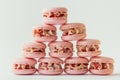 Pink strawberry macaroons decorated with golden petals and freeze-dried red berries stacked together in the shape of pyramid.