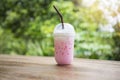 Pink strawberry milk pink ice drink in plastic cup juice for summer and straw on wooden table with nature Royalty Free Stock Photo