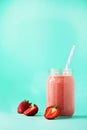 Pink strawberry milkshake in glass jar on blue background with copy space. Summer food concept, vegan diet. Pink Royalty Free Stock Photo