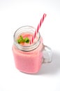 Pink strawberry smoothie in a mason jar glass with straw and scattered berries on white background. Royalty Free Stock Photo