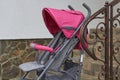 Pink stroller near the railing,there is an empty cart near the stairs near the metal railing