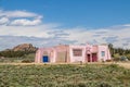 Pink stucco house in sagebrush field with mountian-rock formation and other houses in background in US Southwest Royalty Free Stock Photo