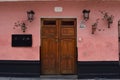 Pink stucco, potted geraniums, 19th century wood doors and wrought iron