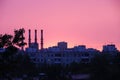 Pink stunning sunset, urban areas, shade trees, pipe plants and silhouettes of blocks of flats Royalty Free Stock Photo