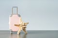 Pink suitcase with seashell on light gray background with copy space.
