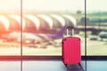 Pink suitcases in airport departure lounge, airplane in background Royalty Free Stock Photo