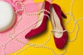 Pink summer women`s hat, red shoes and pearl beads lie on a yellow background Royalty Free Stock Photo