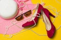 Pink summer women`s hat, red shoes, sunglasses and pearl beads lie on a yellow background Royalty Free Stock Photo