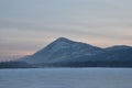 Pink Sunrise over a snowy mountain peak with frozen lake in the Royalty Free Stock Photo