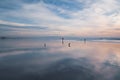 Pink sunset on the beach. Seashore with walking people, cloudy sky, and beautiful sky reflections on sandy beach Royalty Free Stock Photo