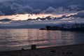 Pink sunset with blue dark clouds in sky in bay of lake Baikal with jetty mole pier with old ships and boats, evening sea, reflect Royalty Free Stock Photo