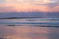 A pink sunset fills in storm clouds over the ocean Royalty Free Stock Photo