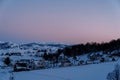 Pink sunset over a snow-covered small village in a mountain valley at the edge of the forest Royalty Free Stock Photo