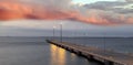 pink sunset at pier street lamp light blurred on sea water wave fluffy cloudy sky at evening Royalty Free Stock Photo