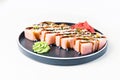 Pink sushi roll in black plate on white background.