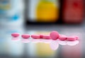 Pink tablets pills on blurred background of drug bottle in drugstore or pharmacy department in hospital. Pharmaceutical industry.